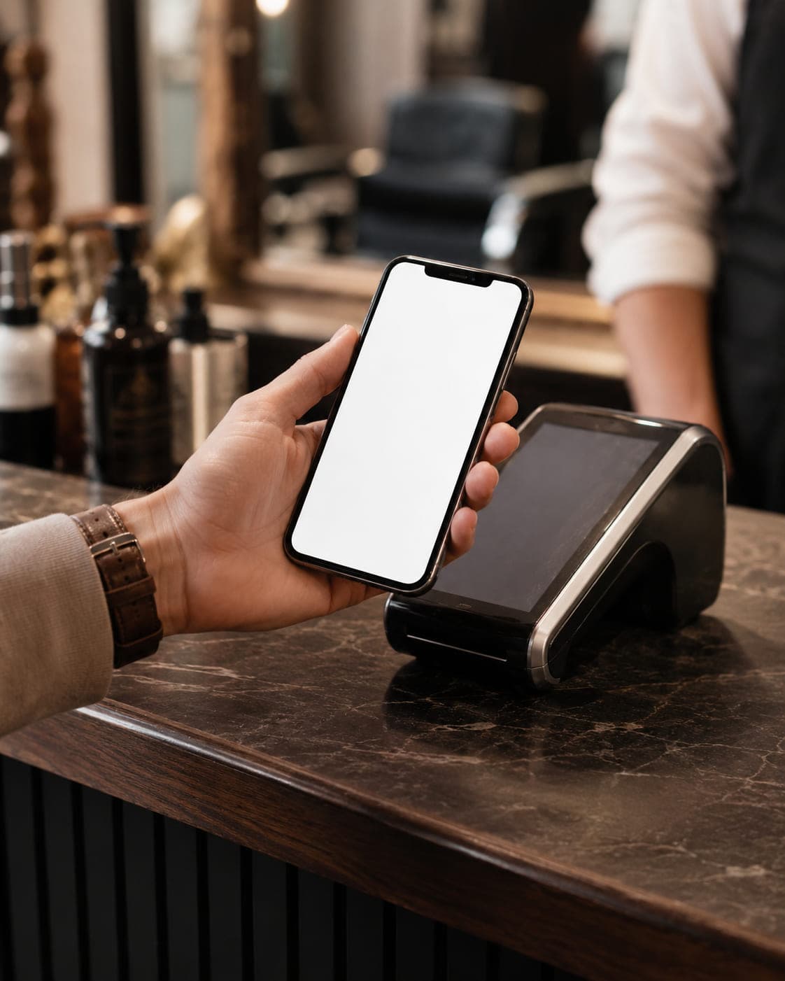 A customer holding a phone with a Stamp loyalty card open in Apple Wallet at a shop terminal